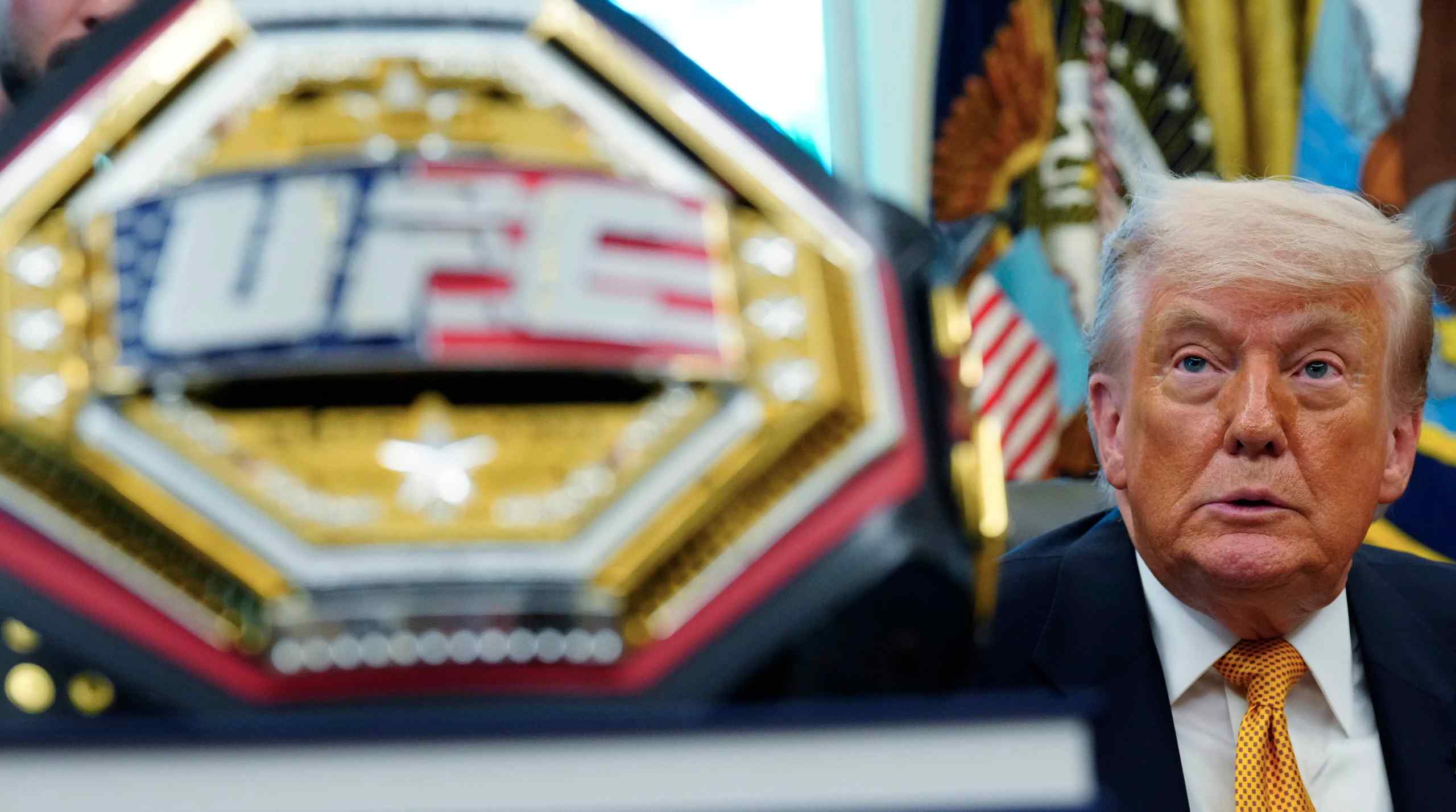A UFC belt in the foreground with President Donald Trump in the background.